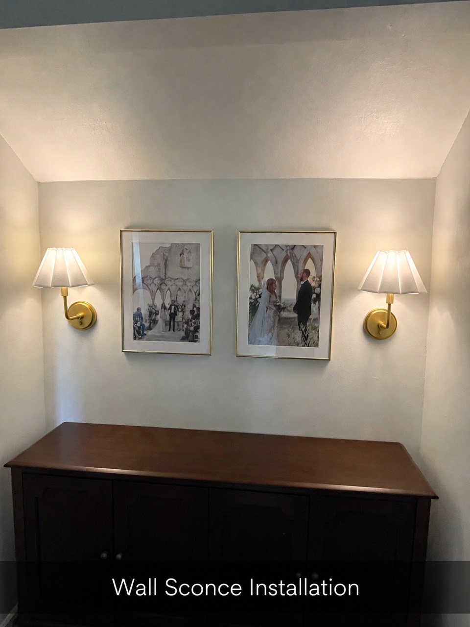 Two installed brass wall sconces illuminated above a cabinet